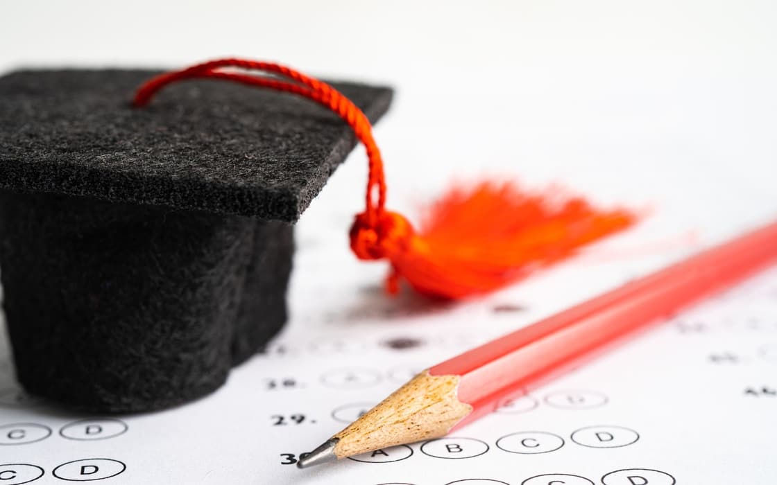 Graduation cap and pencil resting on a multiple-choice answer form