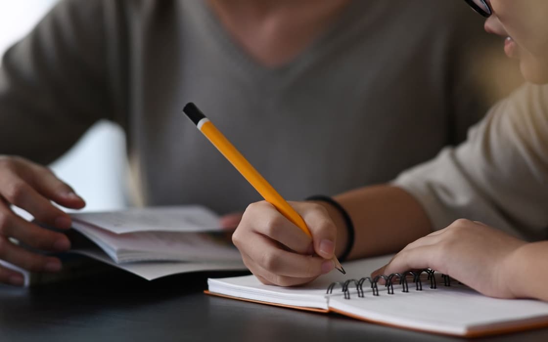 Tutor and student reviewing a notebook together at a desk