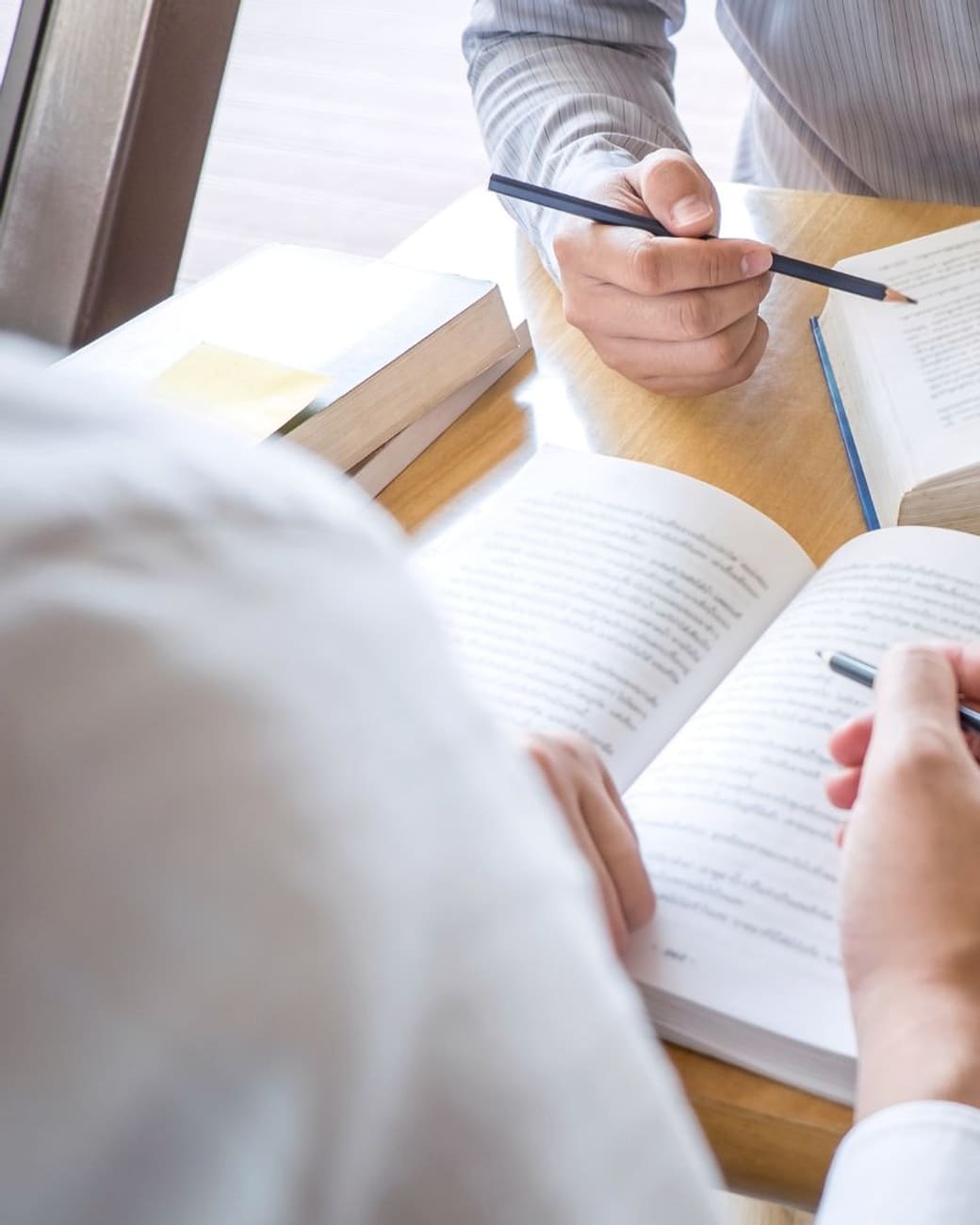 Tutor and student reading side by side with notes in progress