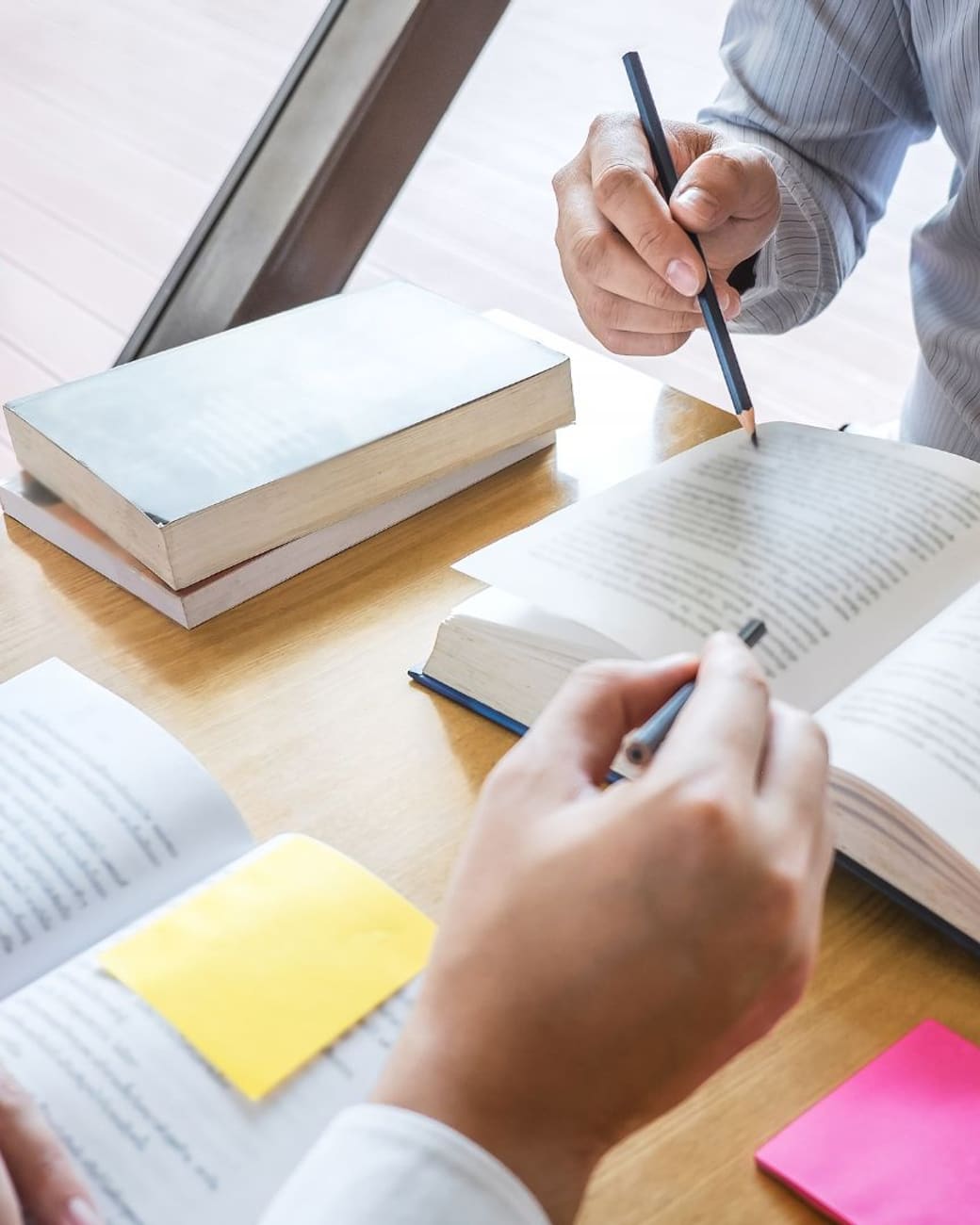 Tutor and student comparing notes across open books at a desk